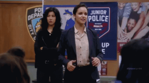 two women are standing in front of a sign that says junior police .
