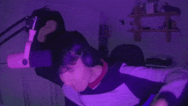 a person is standing in front of a pink microphone with purple lights behind them