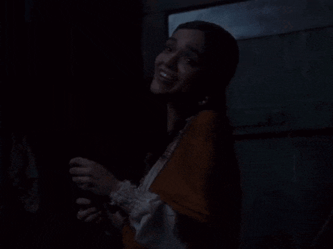 a woman is smiling in a dark room with a blanket around her waist .
