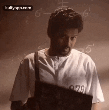 a man in a white shirt with the number 979 on it is standing in front of a wall with numbers on it .