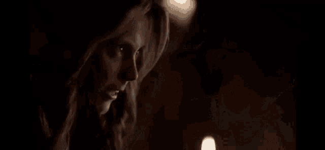 a man in a suit and tie is walking through a dark room with candles on the table .