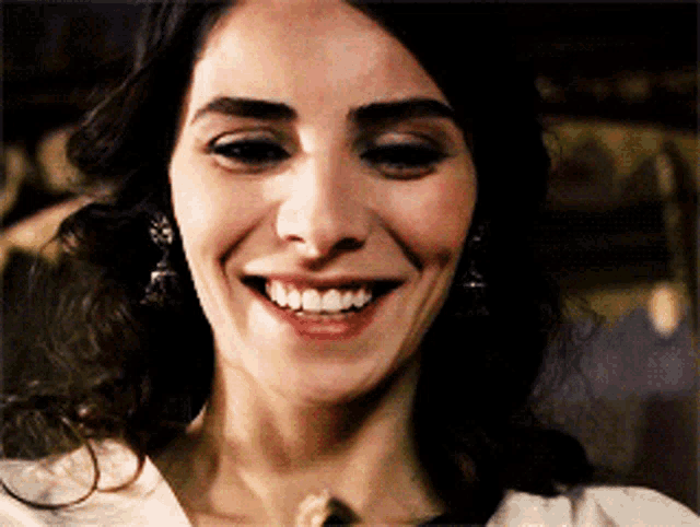 a close up of a woman 's face smiling with a necklace around her neck