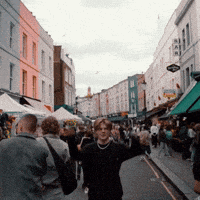 a group of people are walking down a busy street with a sign that says ' a ' on it