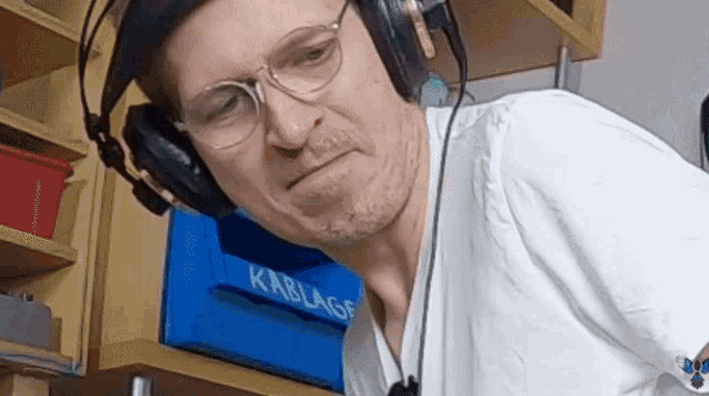 a man wearing headphones stands in front of a sign that says ' kablage '