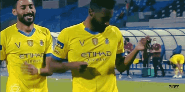 two soccer players wearing yellow jerseys with etihad airways on them