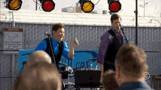 two men singing in front of a sign that says " notice "