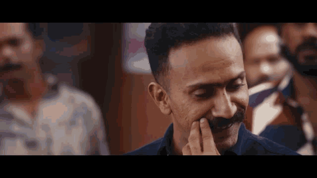 a man with a mustache is touching his face with his hand