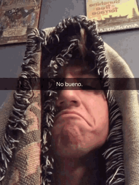 a man with a blanket on his head is making a funny face with the caption no bueno