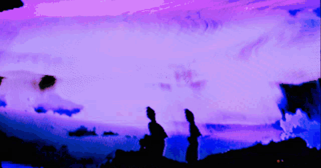 two people standing in front of a purple and blue sky