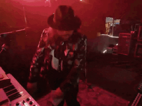 a man in a black hat is dancing in front of a keyboard