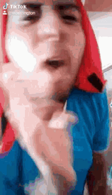 a man with red hair is wearing a blue shirt and a red scarf around his head .