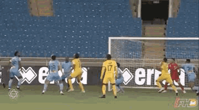 a group of soccer players are playing a game in a stadium with empty seats .
