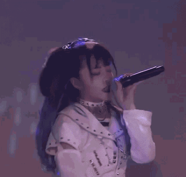 a girl with pigtails is singing into a microphone on stage .