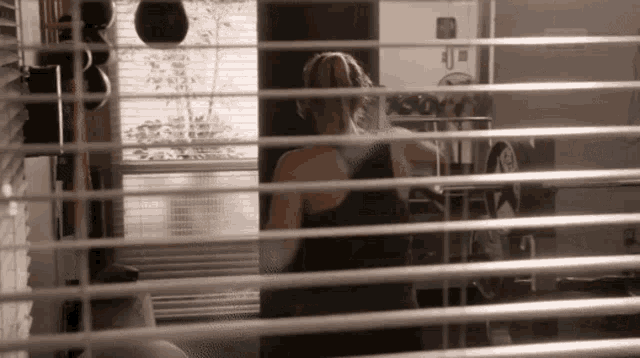 a woman is standing in front of a mirror in a gym behind blinds