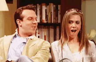 a man and a woman are sitting next to each other with a bookshelf in the background
