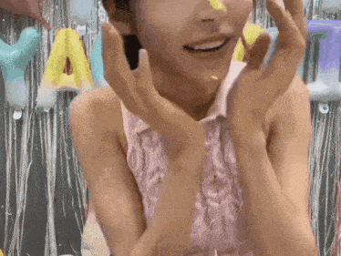 a woman in a pink shirt is smiling with balloons behind her and a sign that says y.