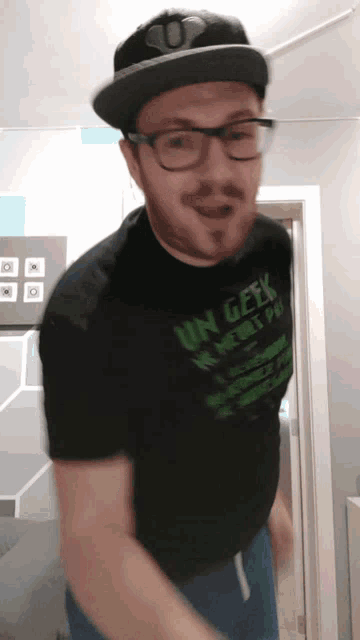 a man wearing a hat and glasses is wearing a shirt that says un geek