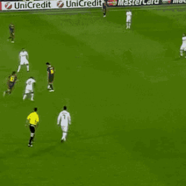 a group of soccer players are playing on a field with a unicredit sign in the background