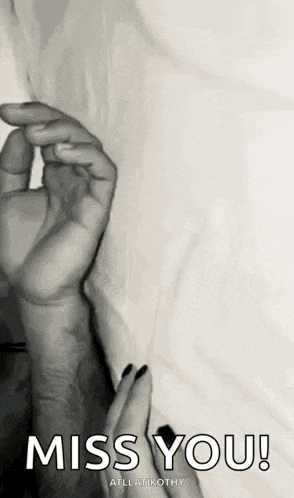 a black and white photo of a person 's hand holding another person 's wrist .
