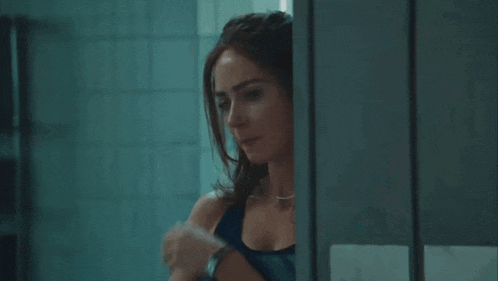 a woman is covering her face with her hand while standing in a bathroom stall .