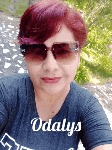 a woman wearing sunglasses and a shirt that says odalys on it