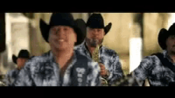 a group of men wearing cowboy hats and shirts are standing next to each other .