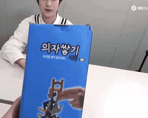 a man sitting at a table holding a blue box with asian writing on it