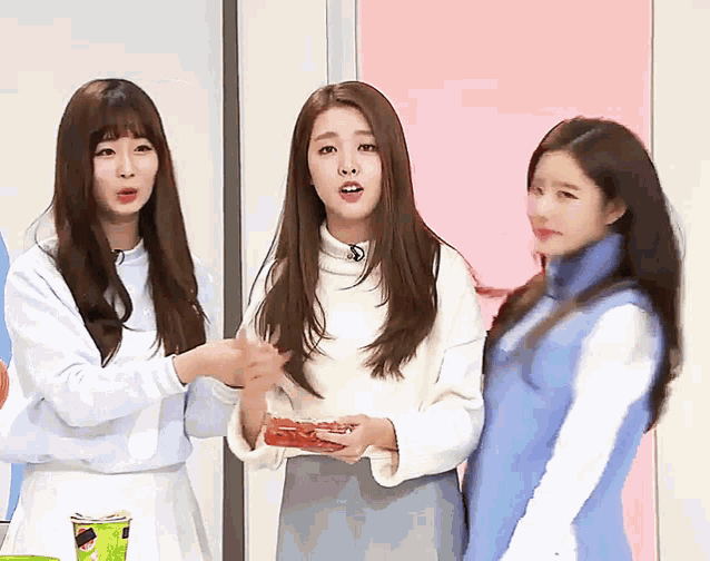 three girls are standing next to each other and one is holding something