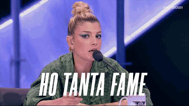 a woman sitting in front of a microphone with the words ho tanta fame behind her