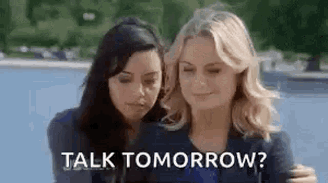 a couple of women standing next to each other with the words `` talk tomorrow '' written on the screen .