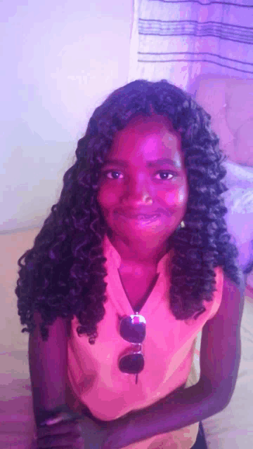 a girl with curly hair wearing sunglasses and an orange shirt