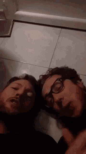two men wearing glasses are standing next to each other on a tile floor