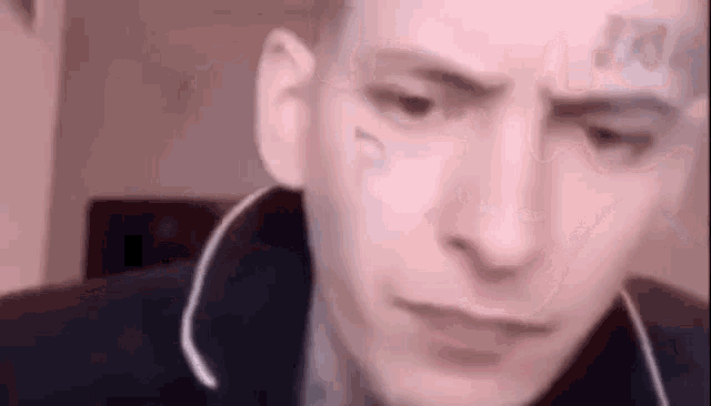 a man with a tattoo on his forehead is making a funny face .