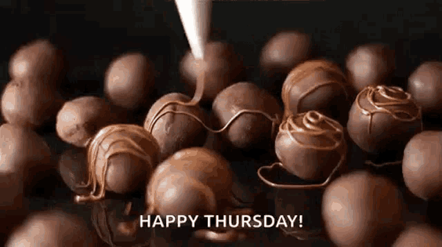 a bunch of chocolate balls are being covered in chocolate and a happy thursday greeting .