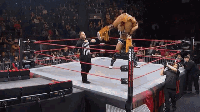 a female wrestler in a ring with a referee and a sign that says wrestling on it
