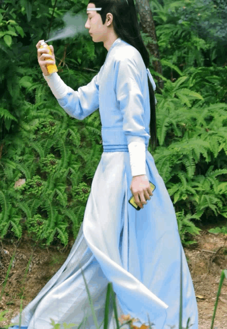 a man in a blue and white dress is spraying something