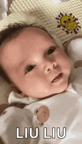a baby is laying on a blanket with a sun on it and making a funny face .