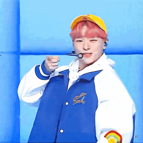 a boy wearing a blue jacket and a yellow hat is pointing at the camera .