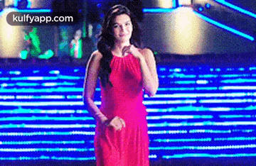 a woman in a red dress is standing on a set of stairs with blue lights behind her .
