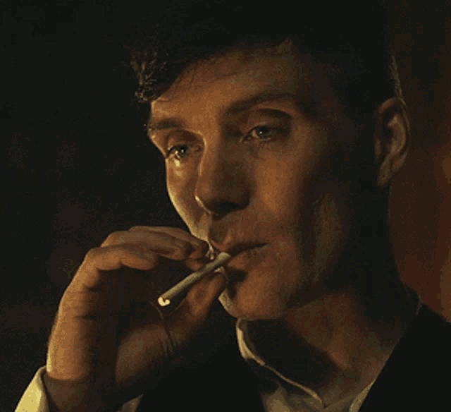 a man in a suit is smoking a cigarette