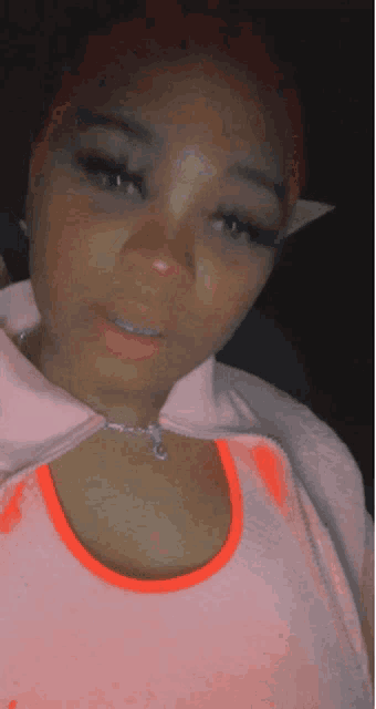 a close up of a woman wearing a pink shirt with the letter c on it