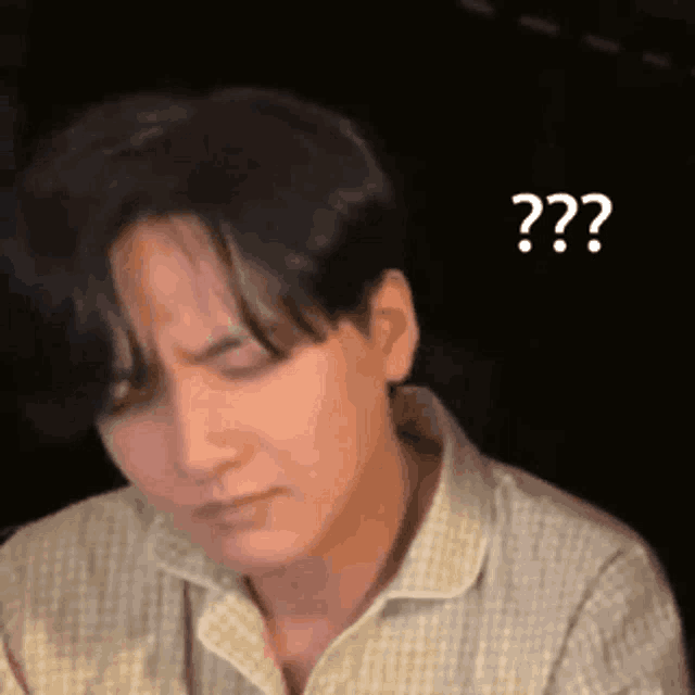 a man in a plaid shirt is making a funny face and asking a question .