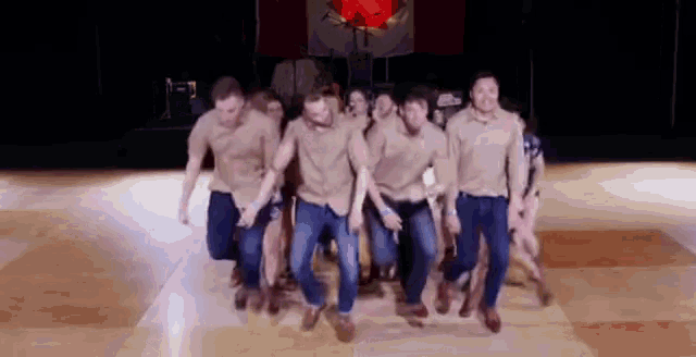 a group of men are dancing together on a dance floor .