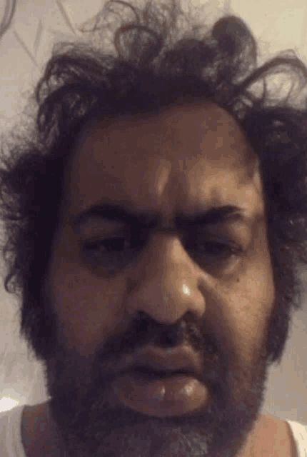 a man with a beard and messy hair is making a face