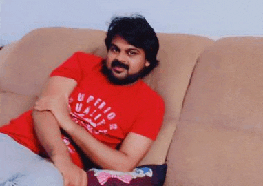 a man is sitting on a couch wearing a red shirt .