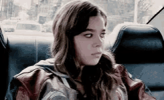 a young woman is sitting in the back seat of a car looking at the camera .