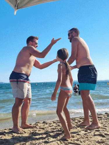 two men and a girl are playing on the beach