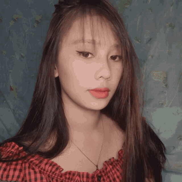 a woman wearing a red plaid off the shoulder top is looking at the camera