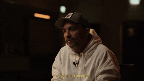 a man wearing a hat and a white hoodie says " it 's something else "