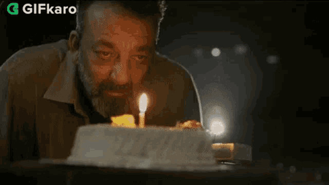 a man with a beard is blowing out a candle on a cake